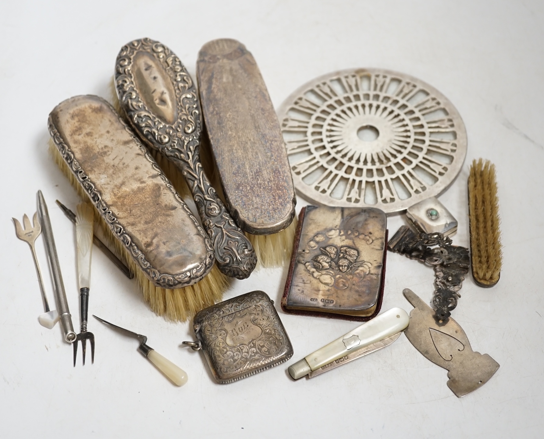 A collection of mostly silver items to include a rattle in the form of a cat, a vesta case, silver backed brushes and a bookmark in form a of trowel, largest 16.5cm wide. Condition - poor to fair